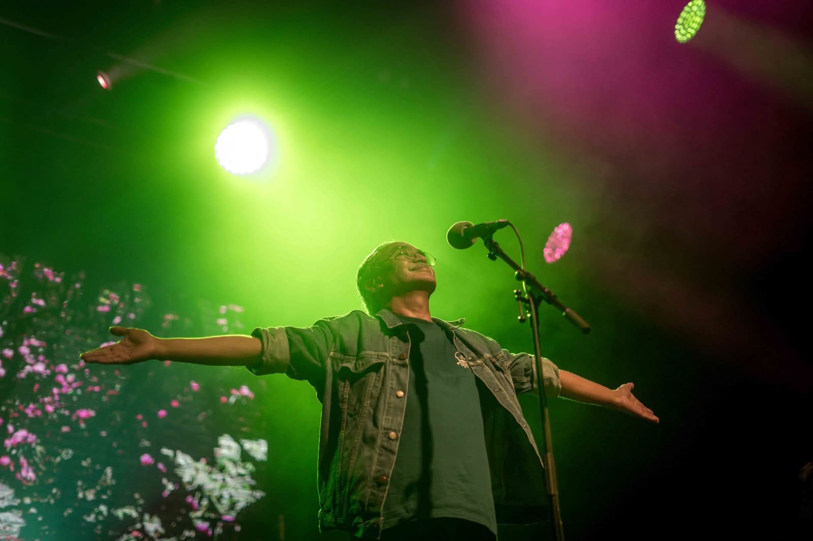 Vocalist with arms outstretched in green stage light